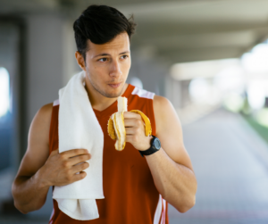 Noi que menja un plàtan, abans de fer esport. L'alimentació és bàsica per a un bon rendiment esportiu